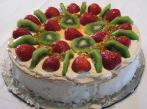 Jose Mier Pavlova dessert topped with kiwi fruit, strawberries and passionfruit; public-domain photograph by Hazel Fowler